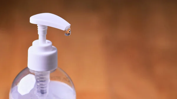 Ahşap arka planda şeffaf el dezenfektanı jeli beyaz, temiz plastik bir şişe, Coronavirus covid-19 konsepti ve el hijyeni.