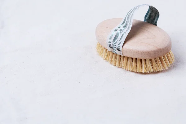 Natural wooden brush for dry body brushing on a beige organic cotton fabric with copy space