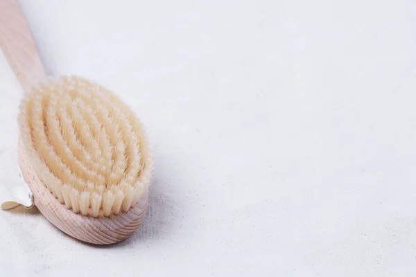 Kuru vücut için doğal ahşap fırça. Bej rengi organik pamuk kumaşı üzerinde fotokopi alanı ile fırçalamak.