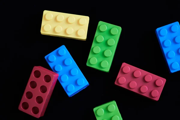 Yeşil, sarı ve kırmızı tuğlalar siyah arka plana rastgele yayılmış. Çocuk oyuncakları, oyun, montessori eğitimi ve öğrenimi kavramı