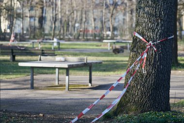 Eğlence parkındaki ağaçtan sarkan bir polis kordonu eğlence faaliyetleri yasaklandıktan sonra covid-19 nedeniyle risk altında. Kolluk kuvvetleri, salgın, polis kısıtlaması ve suç mahalli kavramı