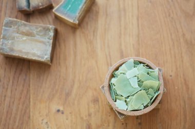 Halep sabununun düz bir tepe görüntüsü ve ahşap arka planda yeşil rengini gösteren kesikler vardı. Hijyen ve dermatoloji kavramı, covid-19 ve virüs önleme, sürdürülebilir ve sıfır atık yaşam