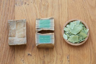 Flat lay overhead shot of an Aleppo bar soap and cuts showing its green color on a wooden background. Concept of hygiene and dermatology, covid-19 and virus prevention, sustainable and zero waste life clipart