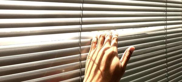 Mão dando uma olhada através das persianas da janela — Fotografia de Stock