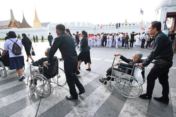 İnsanlar kıdemli tekerlekli sandalye üzerinde ibadet Kral cenazesi için yardım. — Stok fotoğraf