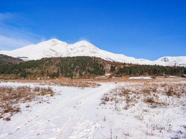 Karlı yolu ve uzaktaki Velino Dağı 'nın zirveleriyle güzel bir kış manzarası. İtalya 'nın orta kesiminde, Abruzzo Apennines' in bir parçası olan L 'Aquila eyaletinin Sahip d' Albe kasabası yakınlarında bir yer..