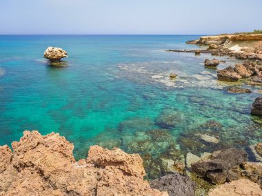 İnanılmaz Kıbrıs manzarası. Resimli, Paralimni kasabasının yakınındaki kayalık plajda sığ ve temiz su var. Turkuaz Akdeniz 'in kumlu kıyıları. Duvar kâğıdı. Yazın aile tatili. Güzel manzara..