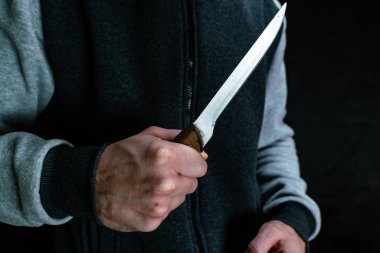 Bir adam elinde bir mutfak bıçağı tutuyor.