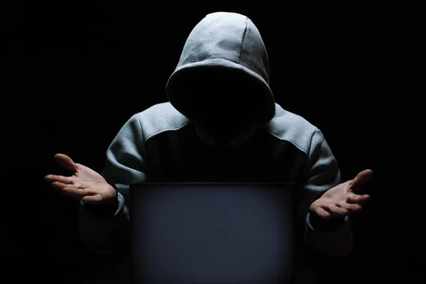 Haker komputerowy wzrusza ramionami niedowierzaniem przed ekranem laptopa — Zdjęcie stockowe