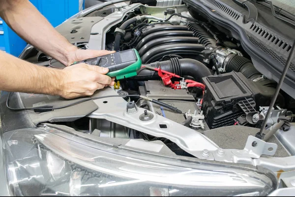 Car service, electrician checks the voltage in the vehicle\'s on-Board network with a tester