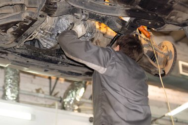 Mechanic in a dirty uniform repairs a car