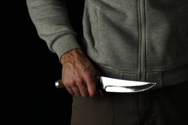 Knife in the man's hand, close-up, on a black background.