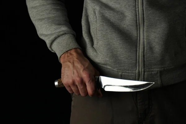 Knife in the man's hand, close-up, on a black background.