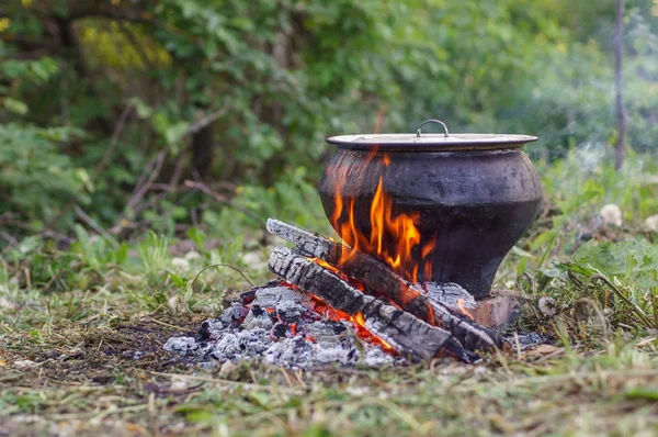 Cast iron on the fire, close-up. People resting in nature, lit a fire and cooked on it in fish soup. — Stock Photo, Image
