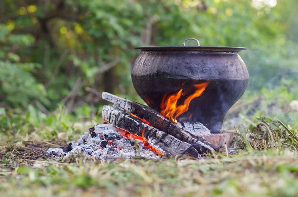 Cast iron on the fire, close-up. People resting in nature, lit a fire and cooked on it in fish soup. — Stock Photo, Image