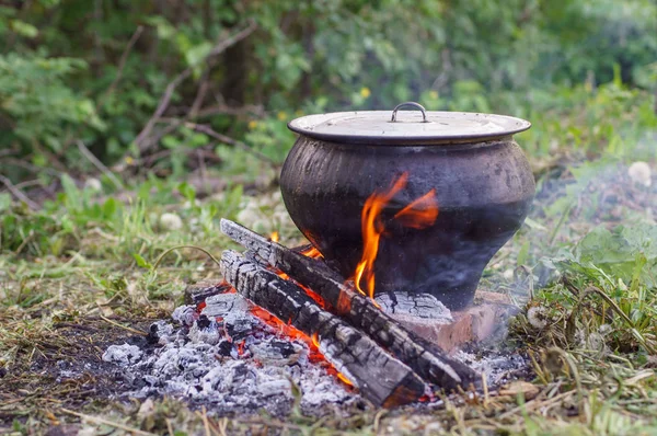 Cast iron on the fire, close-up. People resting in nature, lit a fire and cooked on it in fish soup. — Stock Photo, Image