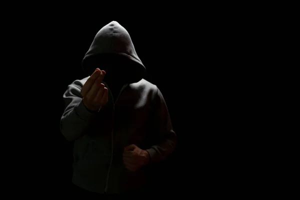 Gizli yüzlü bilinmeyen bir adam karanlıkta dikilirken para sızdırıyor. — Stok fotoğraf