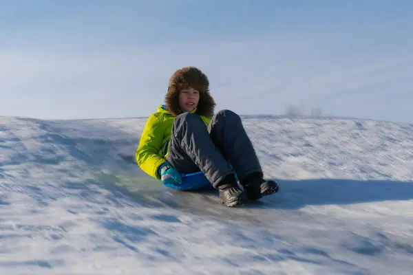 Радостный мальчик едет на ледяной горке — стоковое фото