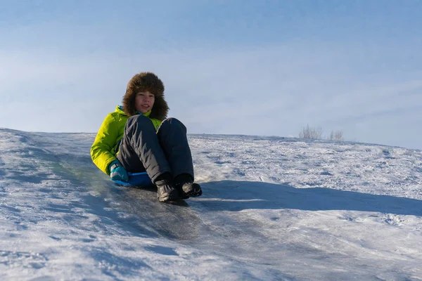 Засохший мальчик скользит по ледяной горке — стоковое фото