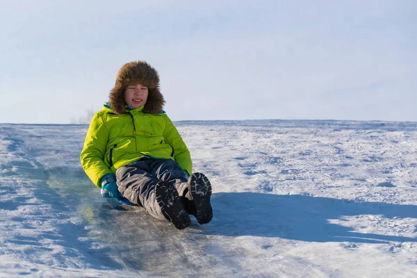 El niño se desliza a lo largo del deslizamiento de hielo en el hielo y cierra los ojos con miedo —  Fotos de Stock