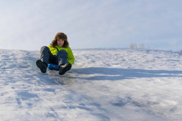 Веселый мальчик скользит по ледяной горке — стоковое фото