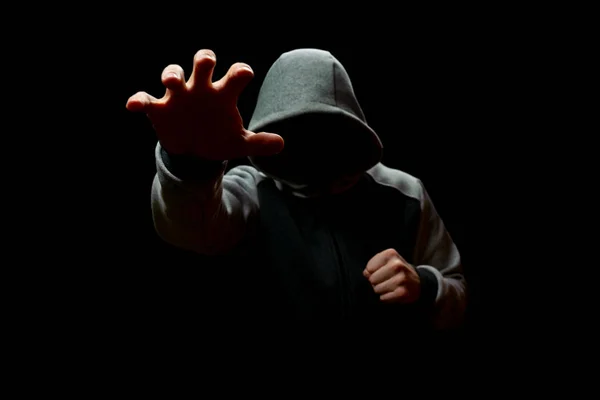 Un hombre en una capucha se extiende de la oscuridad. Robo y Fraude — Foto de Stock