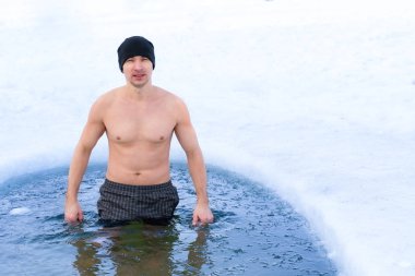 Kışın buz çukurunda soğuk suda yüzmeden önce şapkalı genç bir adam. Sağlıklı yaşam biçimi, kopyalama alanı