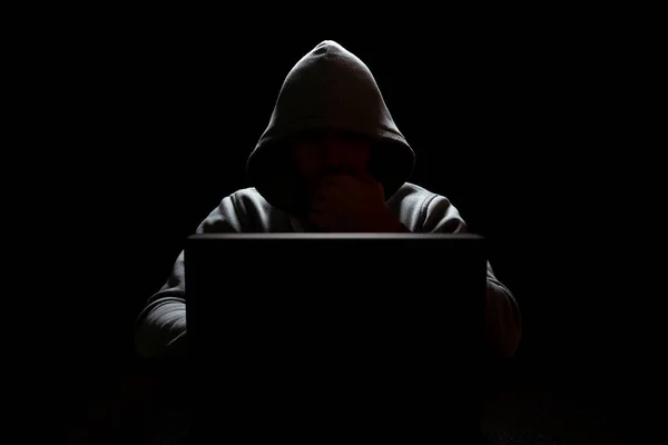 Ein Computerhacker vor einem Laptop legte im Dunkeln seine Hand vor sein Gesicht — Stockfoto