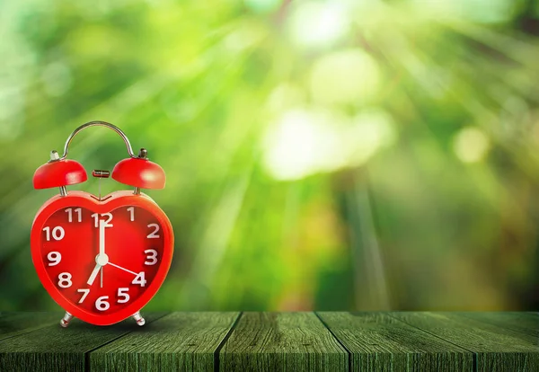 Horloge rouge sur 7 heures mettre sur table en bois — Photo