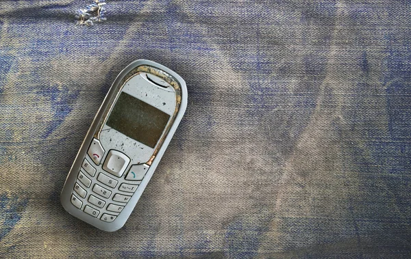 Vintage mobile phone put on old denim background — Stock Photo, Image