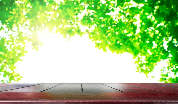 Ξύλινη επιτραπέζια με φρέσκο πράσινο της φύσης θολή φόντο — Φωτογραφία Αρχείου