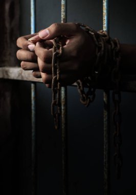 Prisoner with chain holding prison bar clipart