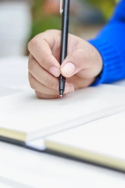 Mão feminina com camisa primavera escrevendo algo com caneta — Fotografia de Stock