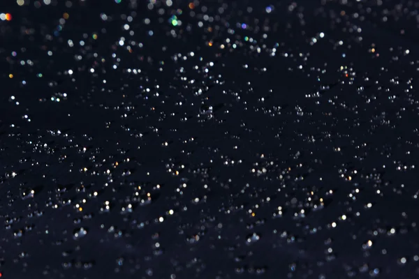 Wassertropfen mit Regenbogenglitzern auf dunklem Hintergrund. — Stockfoto