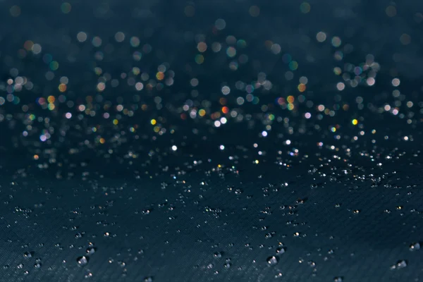 Gotas de agua con brillo de arco iris sobre un fondo oscuro . — Foto de Stock