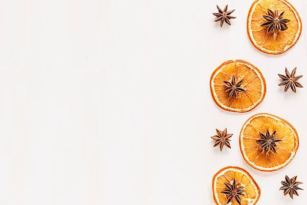 Weihnachtsessen - Glühweinhintergrund. dekorativer Rahmen aus Gewürzzutaten - Anissterne, Zimt, getrocknete Orangen und Wein auf hölzerner weißer Oberfläche. — Stockfoto
