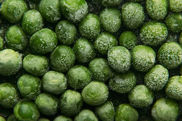 Fresh frozen green peas with hoarfrost closeup as background. — Stock Photo, Image