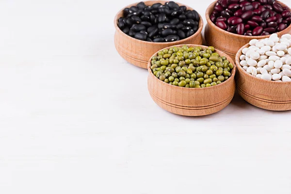 Assortimento di fagioli in una ciotola di legno con spazio copia su sfondo di legno bianco . — Foto Stock