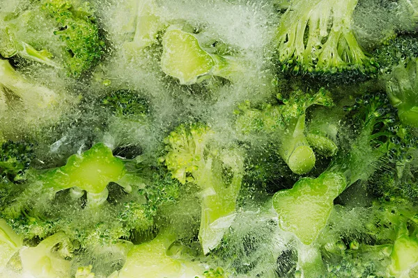 Νωπά κατεψυγμένα πράσινο μπρόκολο σε πάγο closeup ως φόντο. — Φωτογραφία Αρχείου