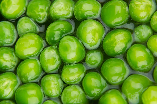 Wet fresh green peas in water closeup as background. — Stock Photo, Image