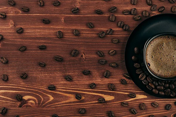 Gorąca kawa w czarny kubek z crema i wzór ziarna z kopia miejsce na brązowy stare podłoże drewniane deska, widok z góry. — Zdjęcie stockowe