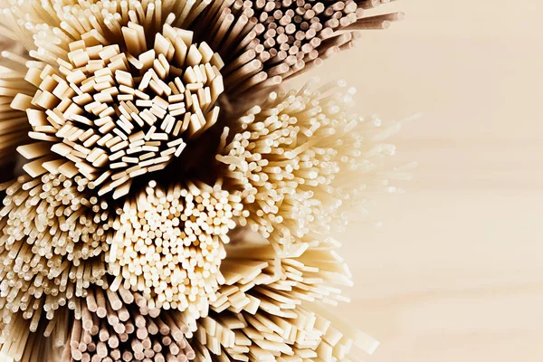 Cross-section of different bundles of raw noodles close up on soft beige wooden board, top view. — Stock Photo, Image