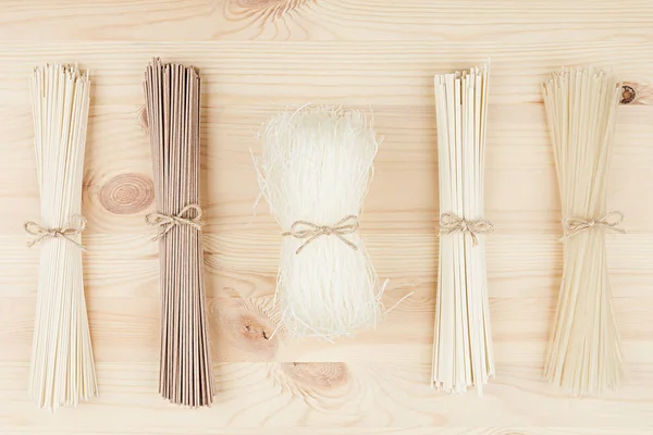 Raw asian noodles close up on beige wooden board background, top view. — Stock Photo, Image