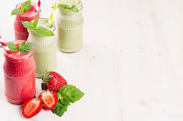 Batido de frutas verdes y rojas en frascos de vidrio con paja, hojas de menta, fresa y manzanas. Fondo de tablero de madera blanco, espacio de copia . —  Fotos de Stock