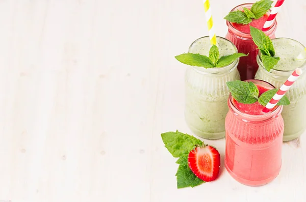 Batido de frutas verdes y rojas recién mezclado en frascos de vidrio con paja, hojas de menta de fresa y manzanas . —  Fotos de Stock
