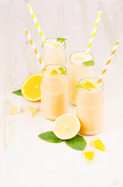 Frullato di limone arancio e giallo appena miscelato in vasi di vetro con paglia, foglia di menta, primo piano . — Foto Stock