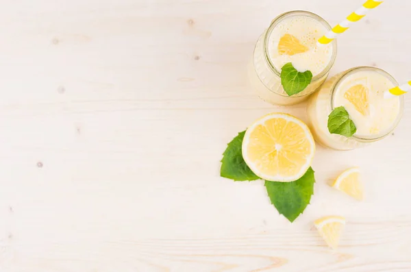 Marco decorativo de batido de limón amarillo en frascos de vidrio con paja, hoja de menta, limón cortado, vista superior . — Foto de Stock