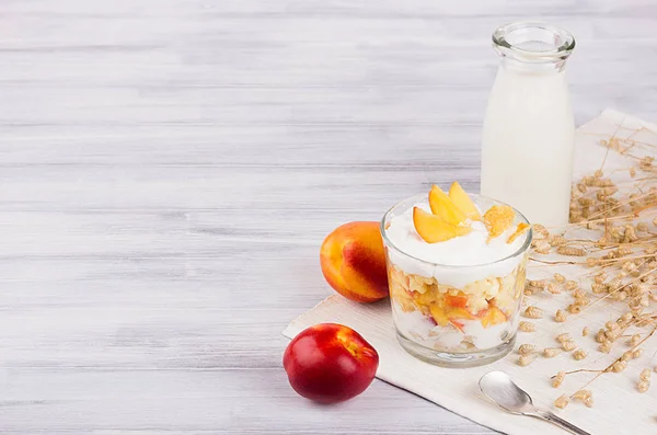 Мягкий завтрак с кукурузными хлопьями, персиком и бутылкой молока на доске из белого дерева . — стоковое фото