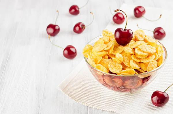 Summer breakfast with golden corn flakes, ripe cherries on white wood board. Decorative border with copy space. — Stock Photo, Image