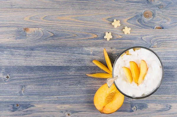 Colorful cheerful smoothie with yogurt, stars corn flakes ripe slice peach on blue wood board, top view. — Stock Photo, Image